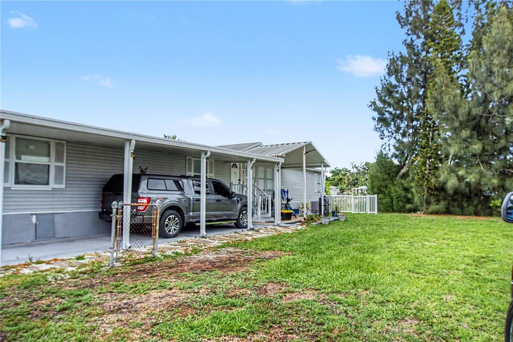 A gray mobile home features a carport with a parked truck and a grassy yard — 6601 51ST WAY N, PINELLAS PARK, FL