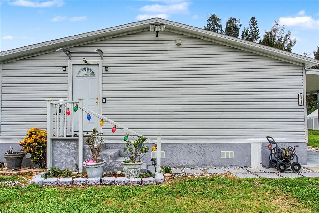 The exterior of a light gray house features a small porch with stairs and lights — 6601 51ST WAY N, PINELLAS PARK, FL