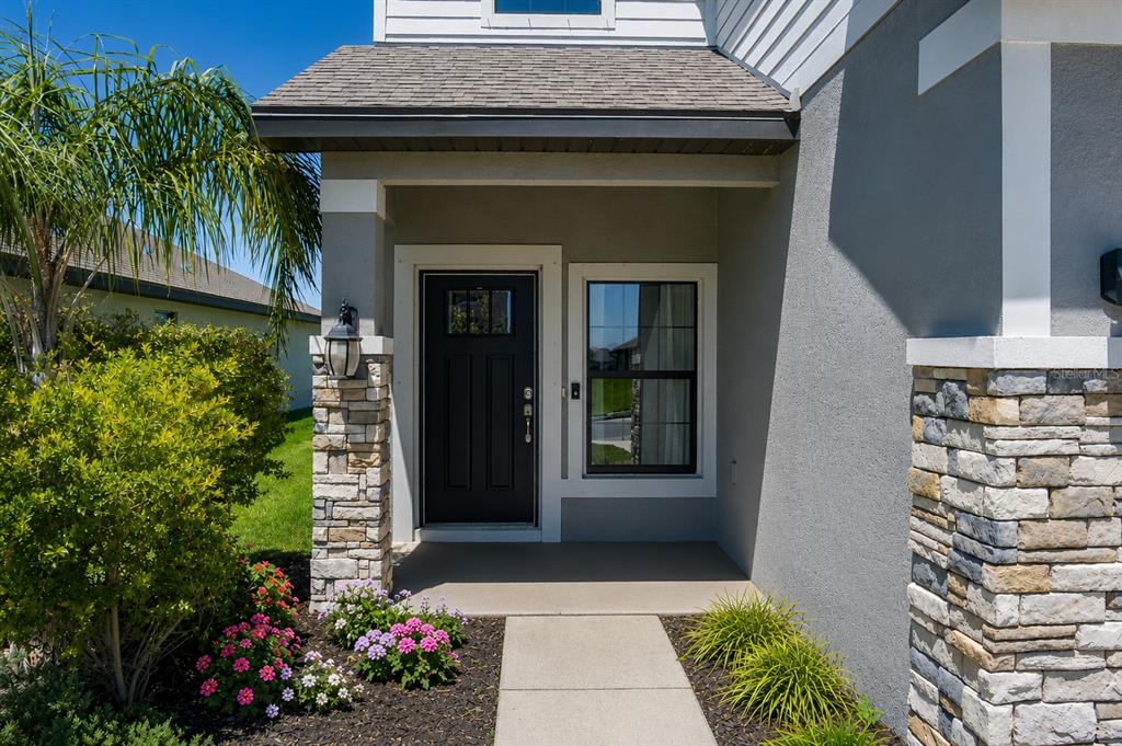 The front entrance features a black door, stone-accented columns, and a concrete walkway — 16121 61ST LANE E, PARRISH, FL