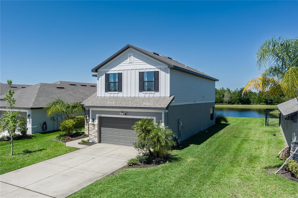 A two-story suburban house with a gray garage, white siding, and a side yard pond — 16121 61ST LANE E, PARRISH, FL