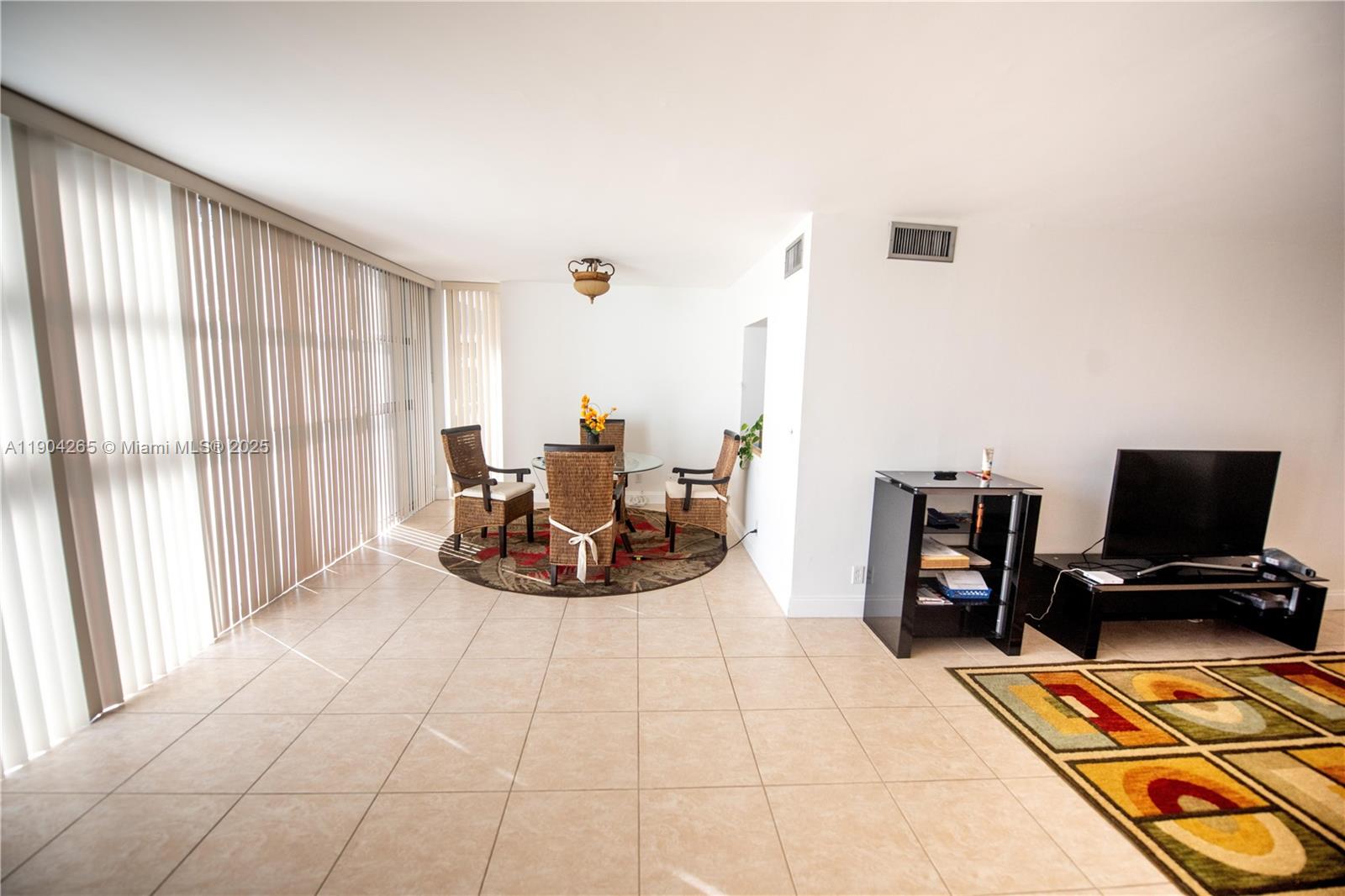 A living and dining area features tile flooring, vertical blinds, and two area rugs — 200 Leslie Dr # 214, Hallandale Beach FL 33009, HALLANDALE BEACH, FL