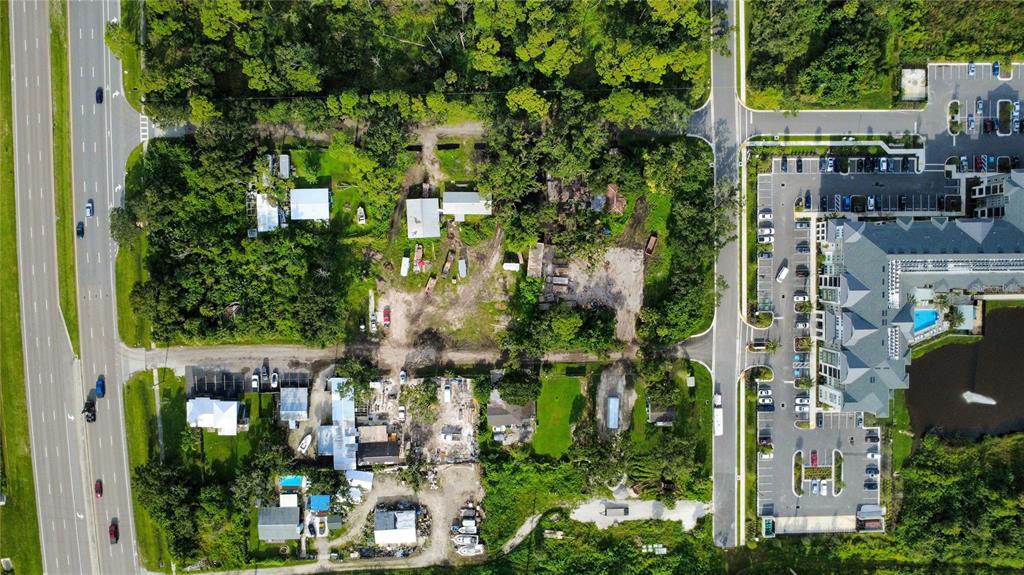 An aerial view shows a wooded lot adjacent to a parking lot and hotel building — 8405 LOUISIANA STREET, SARASOTA, FL