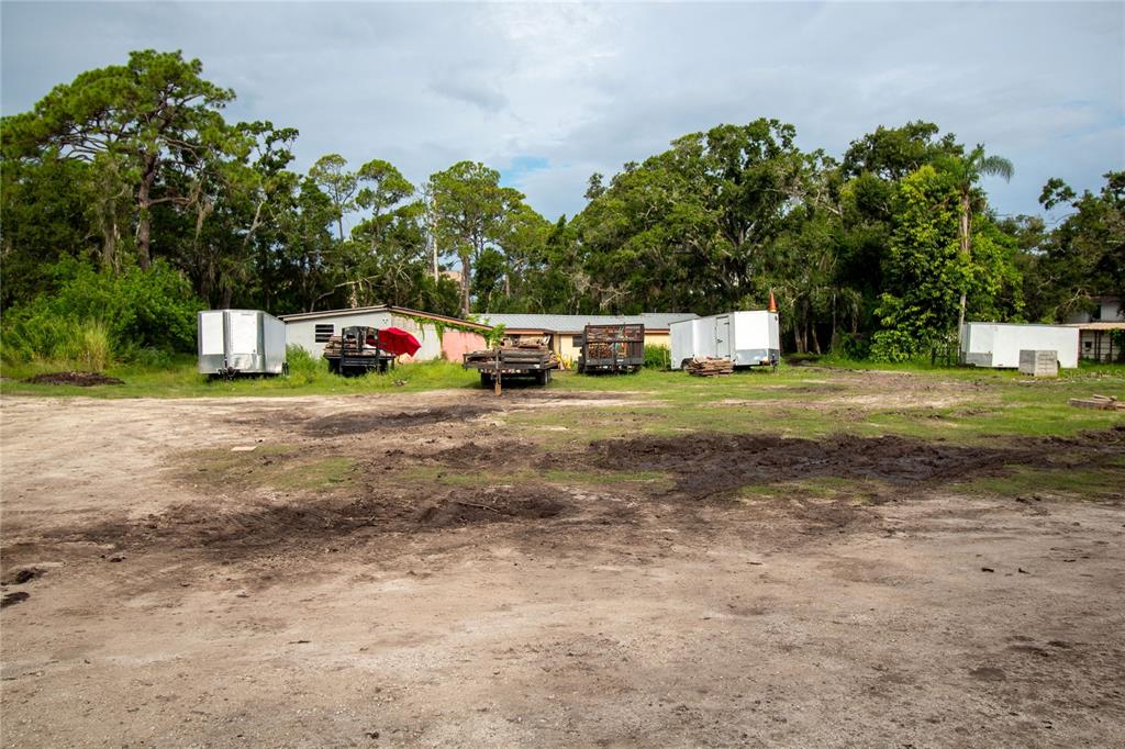 A dirt lot with several trailers parked in front of a house and trees — 8405 LOUISIANA STREET, SARASOTA, FL