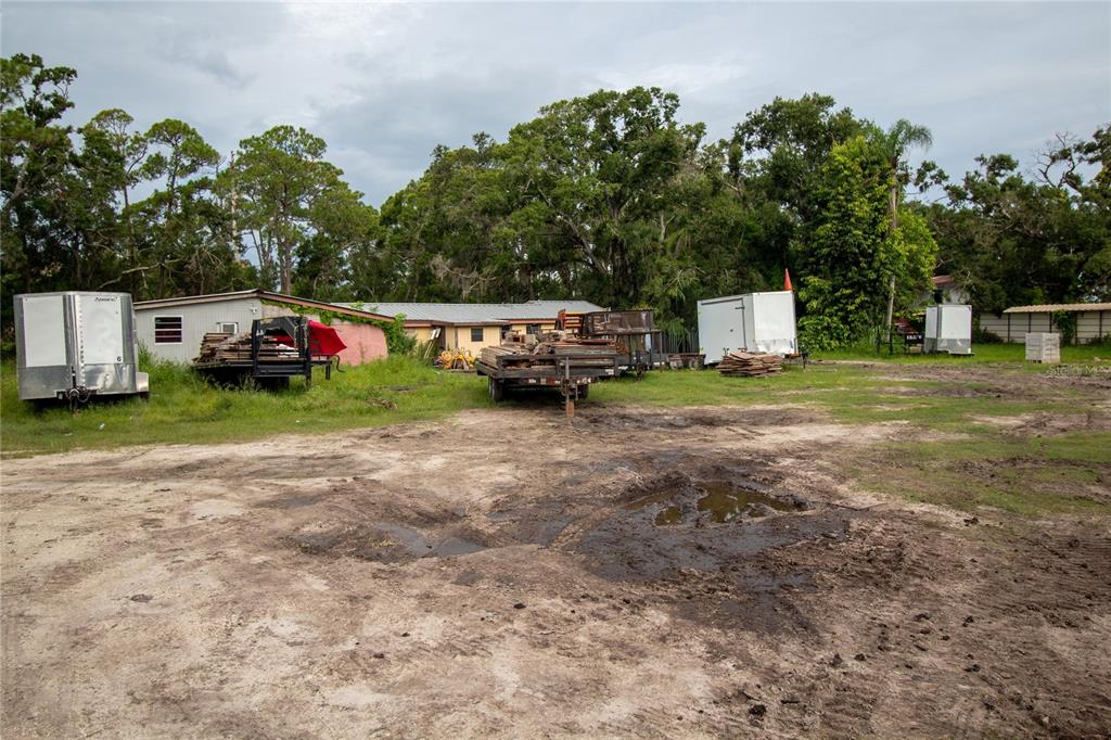 A dirt lot features several trailers and building materials in front of a low-slung building — 8405 LOUISIANA STREET, SARASOTA, FL