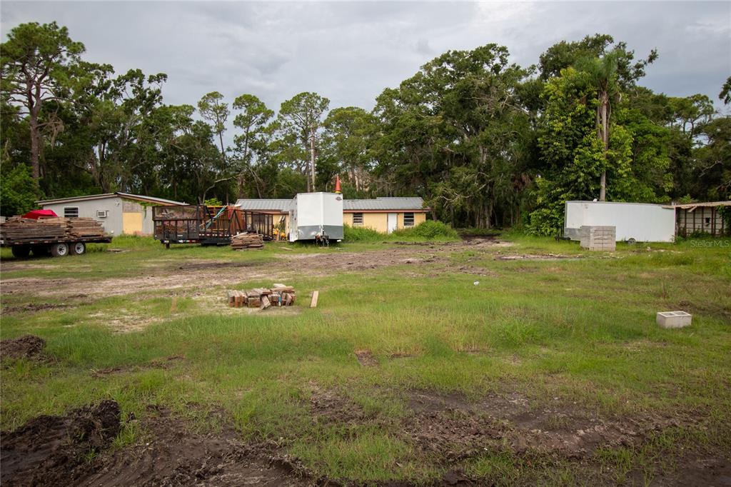 A large, grassy lot features a small house, several trailers, and stacks of lumber — 8405 LOUISIANA STREET, SARASOTA, FL