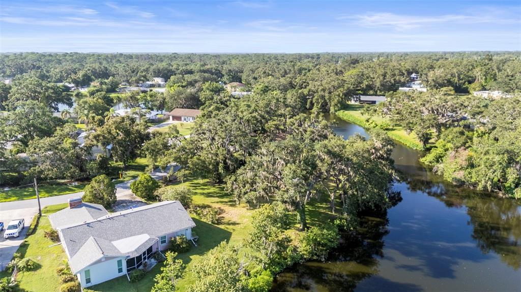 An aerial view shows a house with a gray roof situated beside a winding river — 5405 SAN JUAN DRIVE, SARASOTA, FL
