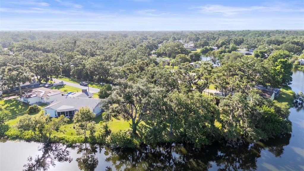 An aerial view shows a house with a screened porch situated along a waterfront lot — 5405 SAN JUAN DRIVE, SARASOTA, FL
