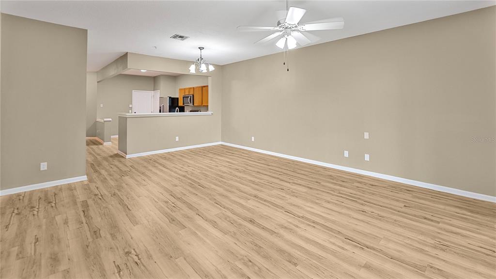 An empty living room with light wood-look flooring, beige walls, and a ceiling fan — 6292 TWAIN STREET UNIT 102, ORLANDO, FL