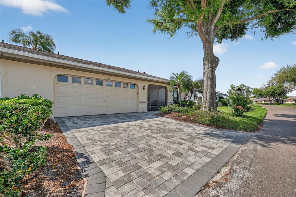 A single-story house with a paved driveway, a two-car garage, and a large shade tree — 2322 LANCASTER DRIVE, SUN CITY CENTER, FL
