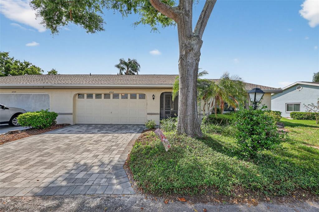 A single-story house with a paved driveway, a two-car garage, and a large front tree — 2322 LANCASTER DRIVE, SUN CITY CENTER, FL