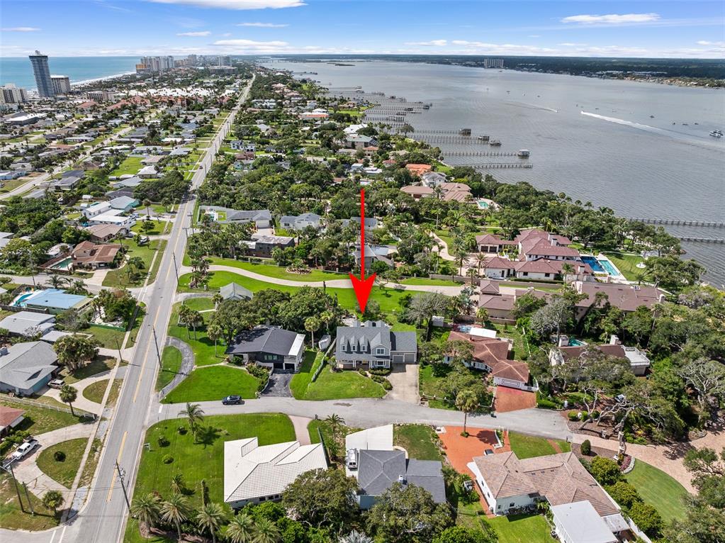 An aerial view shows a residential neighborhood with a red arrow pointing to a house — 2 HICKORY LANE, DAYTONA BEACH, FL