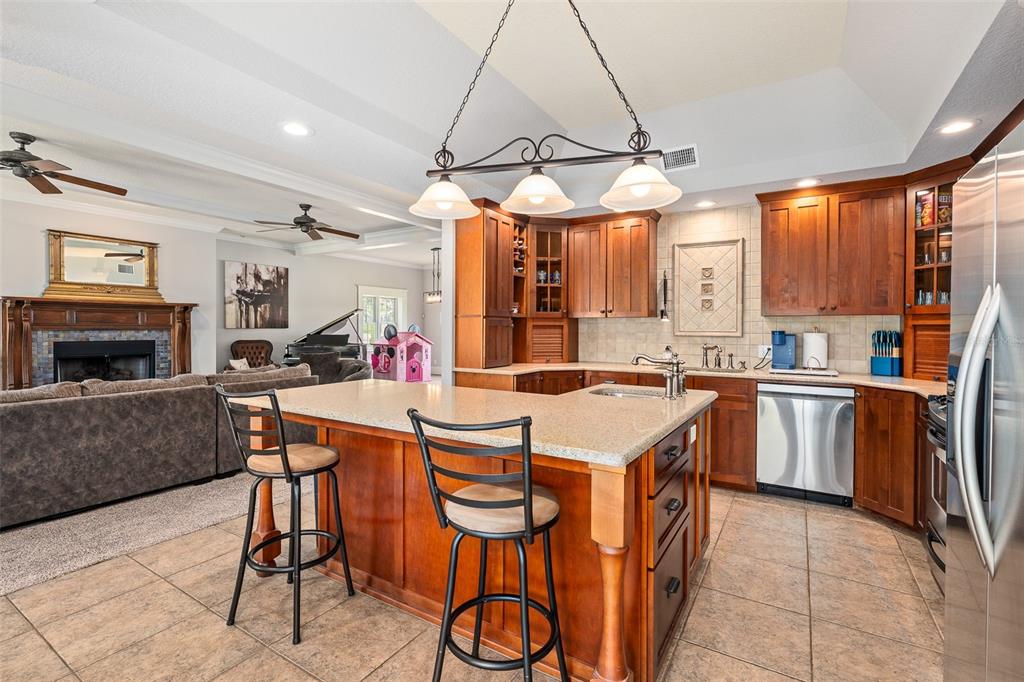 A kitchen with wood cabinets, granite countertops, and a center island with two bar stools — 2 HICKORY LANE, DAYTONA BEACH, FL