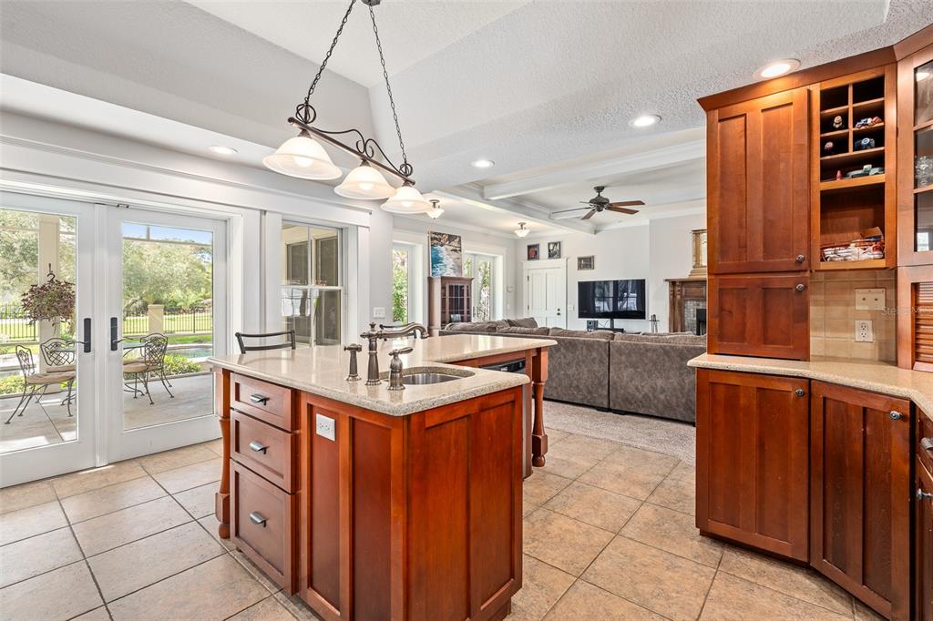 A kitchen with wood cabinets, a granite-topped island, and a view into the living room — 2 HICKORY LANE, DAYTONA BEACH, FL
