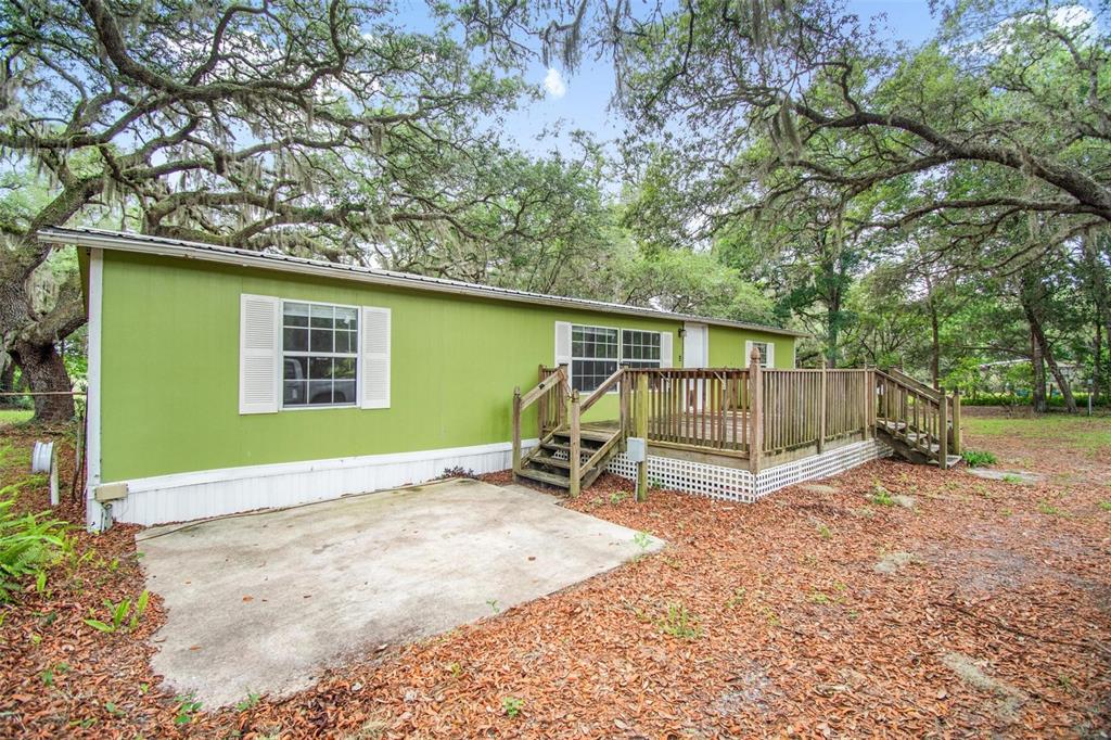 A lime green mobile home features a wooden deck and a concrete patio area outside — 156 KINGFISH ROAD, POMONA PARK, FL