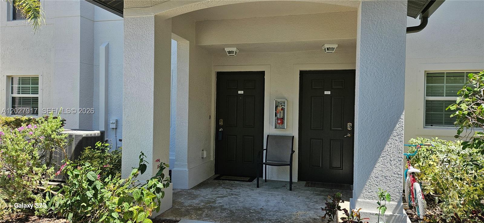 The exterior view shows two dark entry doors under a covered porch with a chair — 9101 GERVAIS # 1705, Naples FL 34120, NAPLES, FL