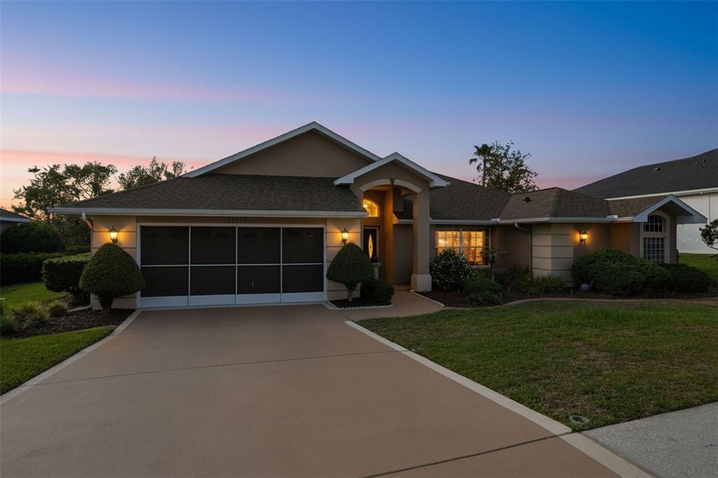 A single-story house with a tan stucco exterior, a two-car garage, and a paved driveway — 13415 BOLTON COURT, SPRING HILL, FL