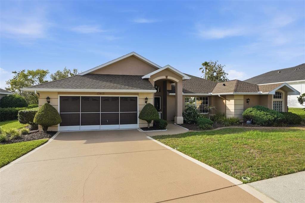 A single-story house with a tan exterior, a two-car garage, and a paved driveway — 13415 BOLTON COURT, SPRING HILL, FL