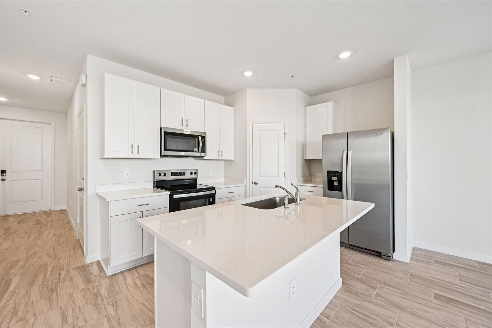 An interior view of an entryway featuring a white door, light walls, and wood-look flooring — 632 Salisbury Circle, Fort Pierce FL 34982, FORT PIERCE, FL