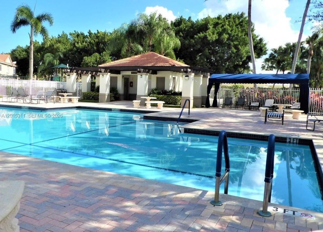 A swimming pool with a depth marker and a covered patio area with outdoor furniture — 800 Sorrento Dr., Weston FL 33326, WESTON, FL