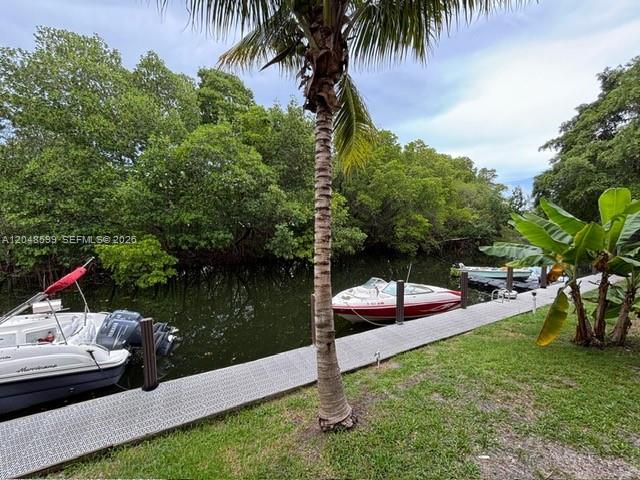 A dock extends into a canal with two boats moored near lush green trees — 1860 Venice Park Dr # 110, North Miami FL 33181, NORTH MIAMI, FL