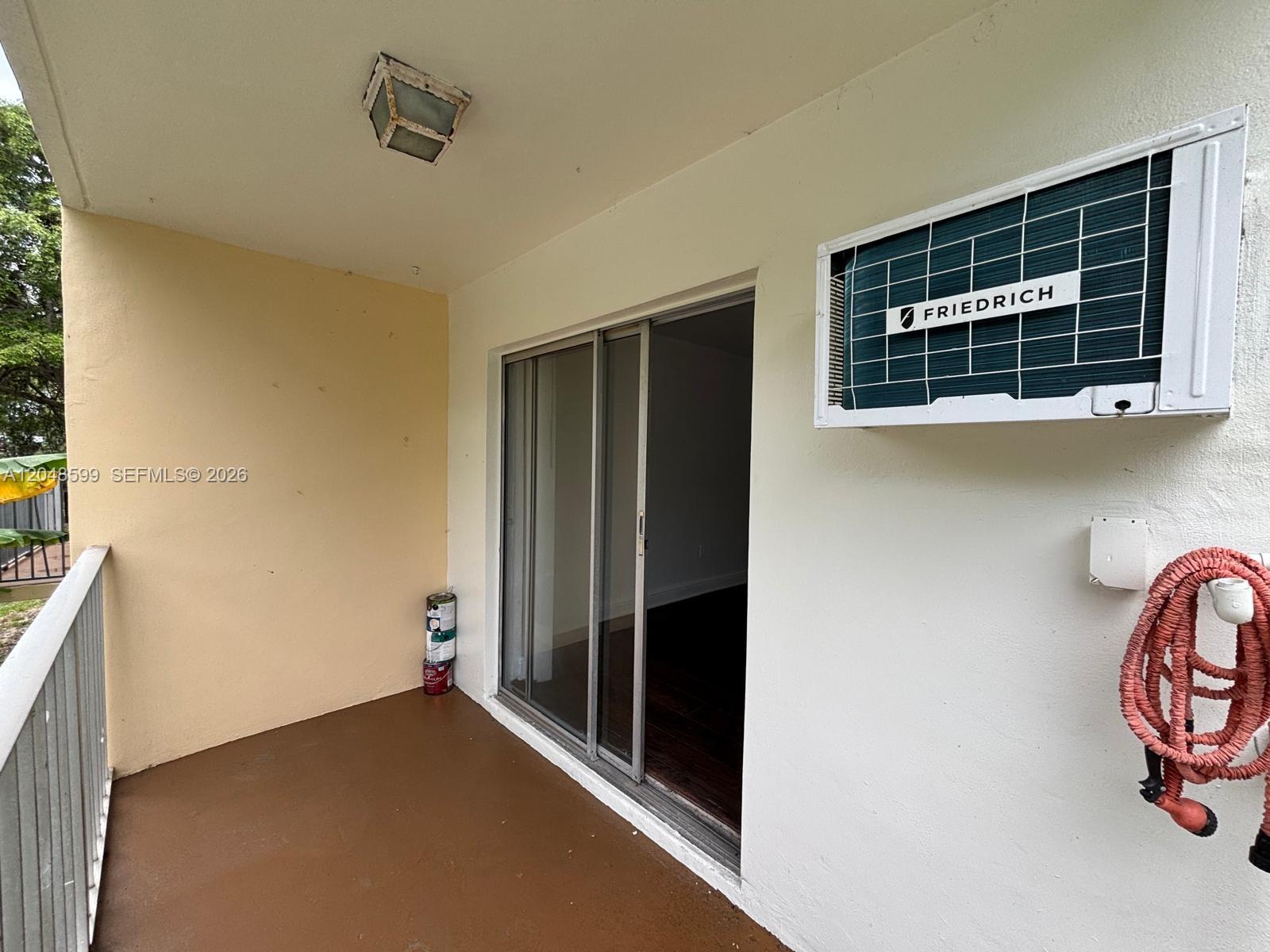 A balcony features a sliding glass door, a wall-mounted Friedrich air conditioner, and a hose — 1860 Venice Park Dr # 110, North Miami FL 33181, NORTH MIAMI, FL
