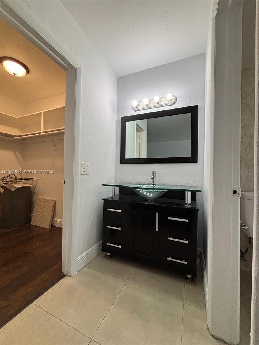 A bathroom vanity with a glass vessel sink sits between a closet and a toilet — 1860 Venice Park Dr # 110, North Miami FL 33181, NORTH MIAMI, FL