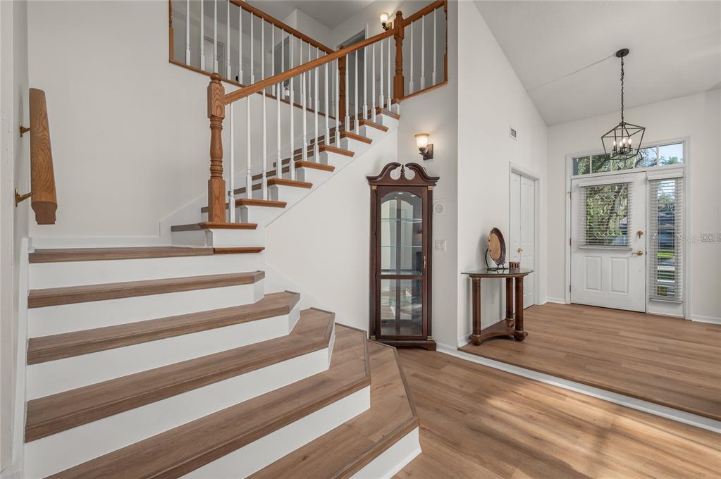 An entryway features a curved wooden staircase with white risers and light wood flooring — 5091 GREAT OAK LANE, SANFORD, FL