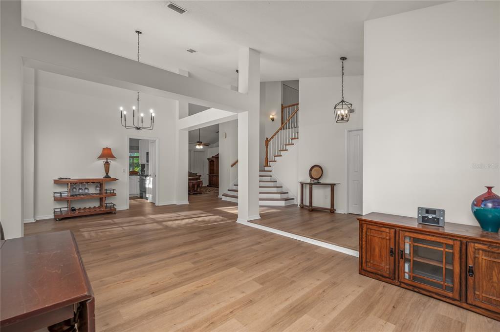A spacious living area features light wood flooring, high ceilings, and a staircase — 5091 GREAT OAK LANE, SANFORD, FL