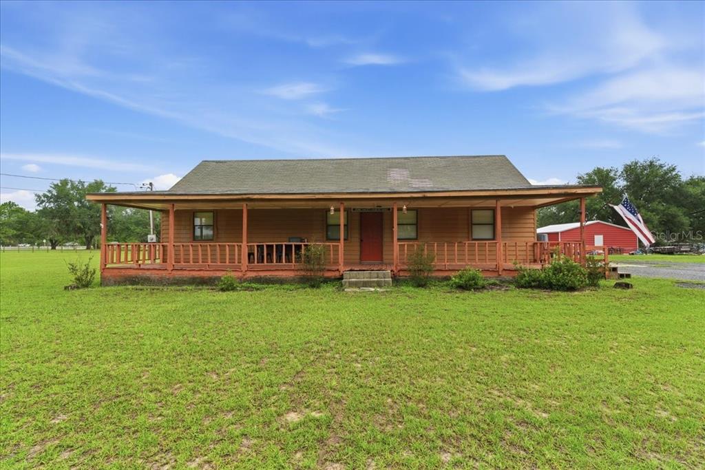 A single-story wooden house with a wide front porch sits on a grassy lot — 5040 RODEO DRIVE, KEYSTONE HEIGHTS, FL