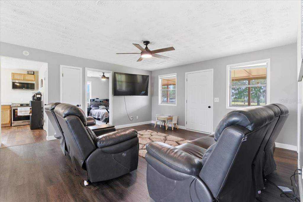 A living room features dark leather recliners, a wall-mounted television, and wood-look flooring — 5040 RODEO DRIVE, KEYSTONE HEIGHTS, FL