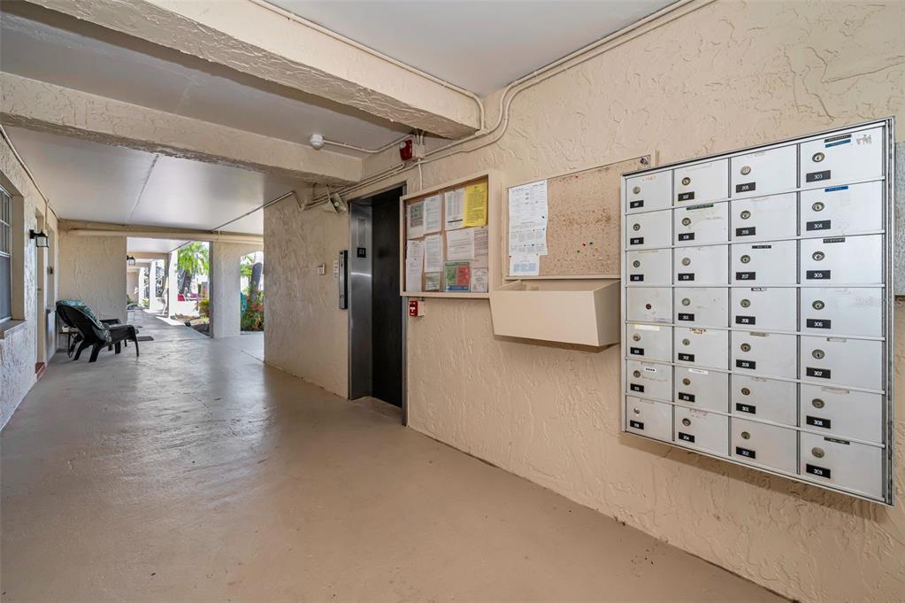 An outdoor hallway features a row of mailboxes, a bulletin board, and an elevator — 936 VIRGINIA STREET UNIT 201, DUNEDIN, FL