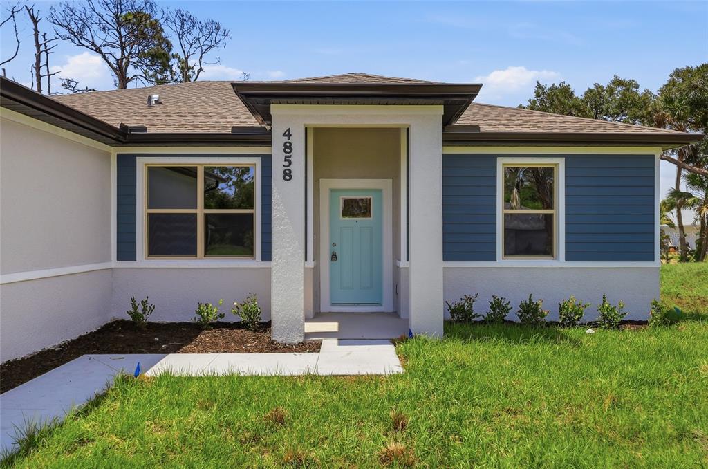 A single-story house exterior features a light blue front door and blue horizontal siding — 4858 FLINT DRIVE, NORTH PORT, FL