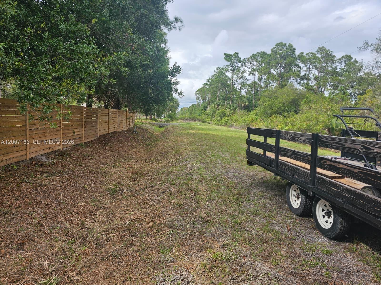 A grassy lot features a wooden fence on the left and a trailer on the right — 820 & 830 S Jasmine Street, Clewiston FL 33440, CLEWISTON, FL