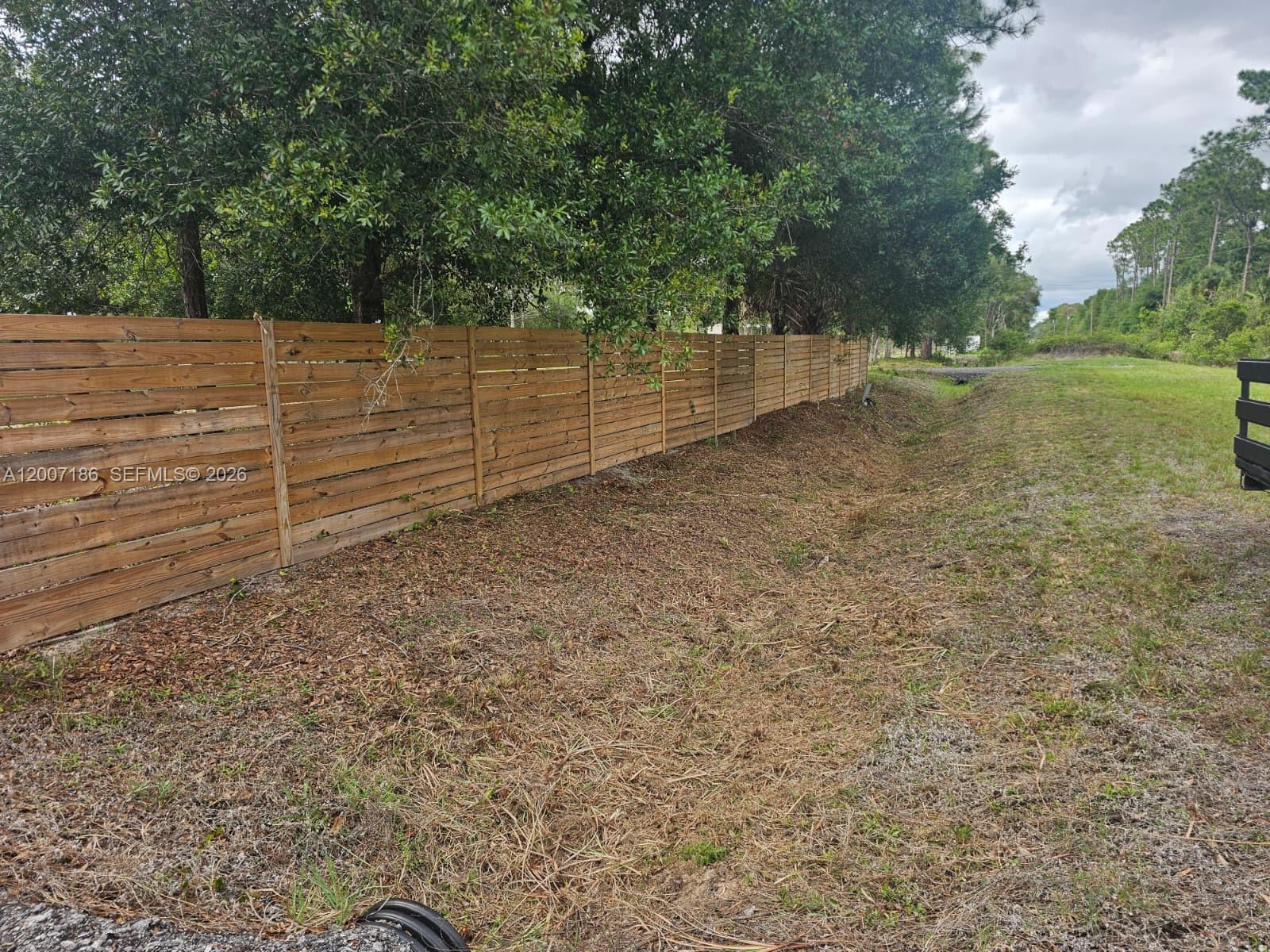 A wooden horizontal slat fence runs along the edge of a grassy, unpaved lot — 820 & 830 S Jasmine Street, Clewiston FL 33440, CLEWISTON, FL