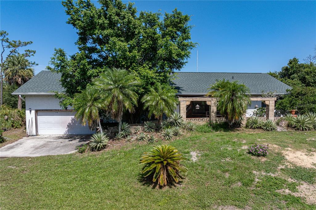 A single-story house with a white garage, a covered porch, and various palm trees — 2065 DUNCAN ROAD, PUNTA GORDA, FL