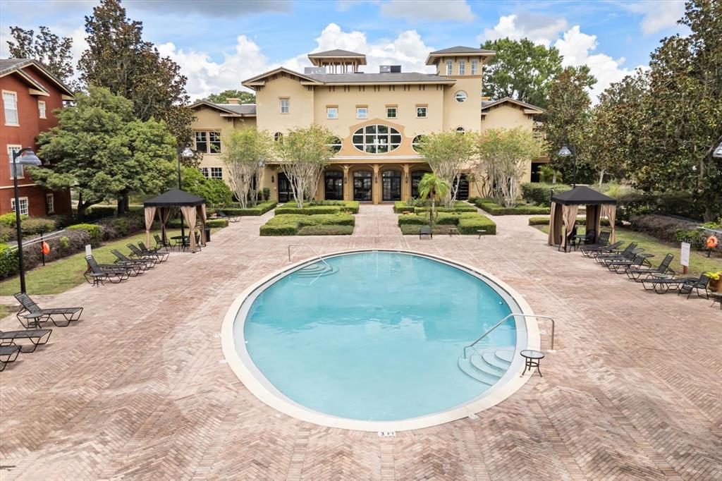 An oval swimming pool sits on a brick patio in front of a large building — 1341 ARBOR VISTA LOOP UNIT 317, LAKE MARY, FL