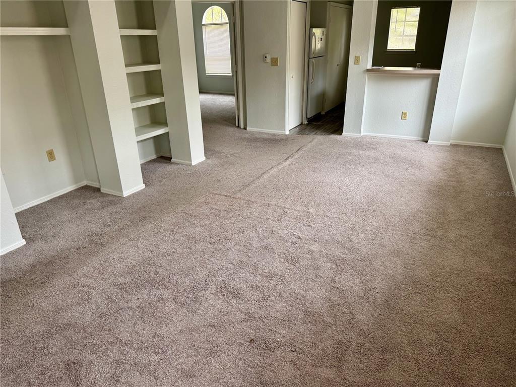 A carpeted living room features built-in shelving and an opening to a kitchen area — 1341 ARBOR VISTA LOOP UNIT 317, LAKE MARY, FL