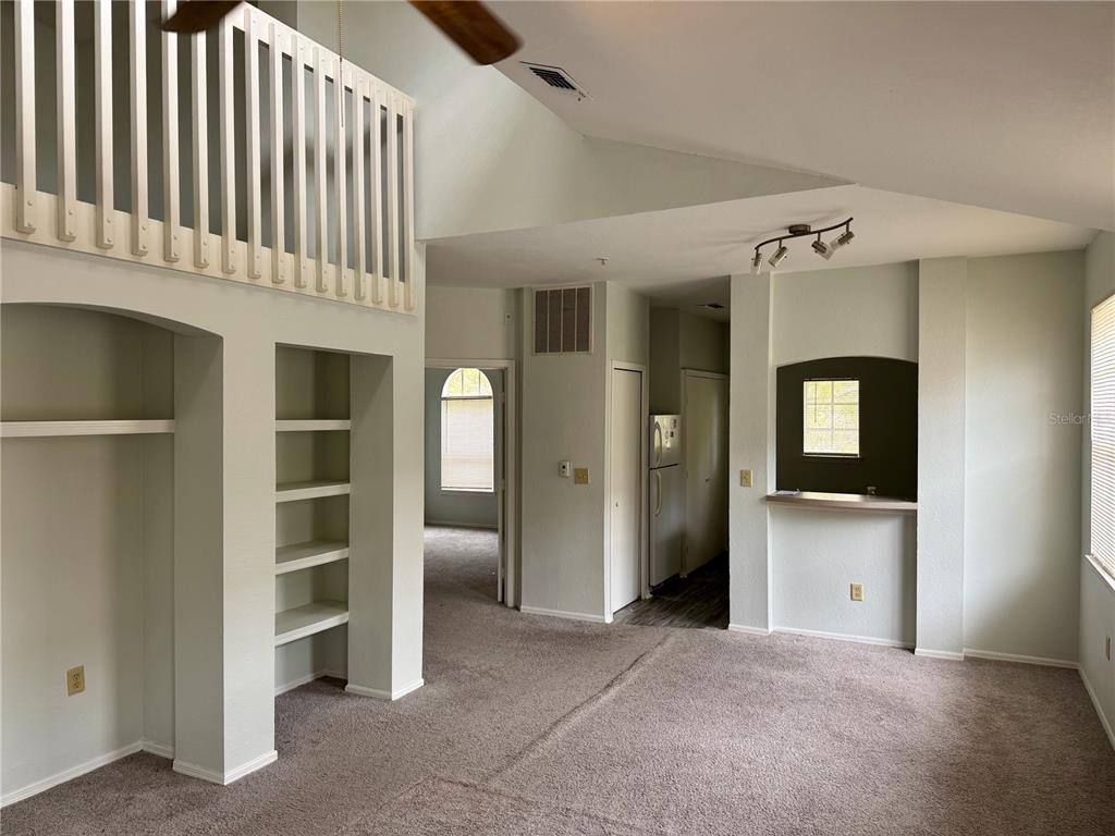 A living room features a vaulted ceiling, a loft railing, built-in shelving, and carpeted flooring — 1341 ARBOR VISTA LOOP UNIT 317, LAKE MARY, FL