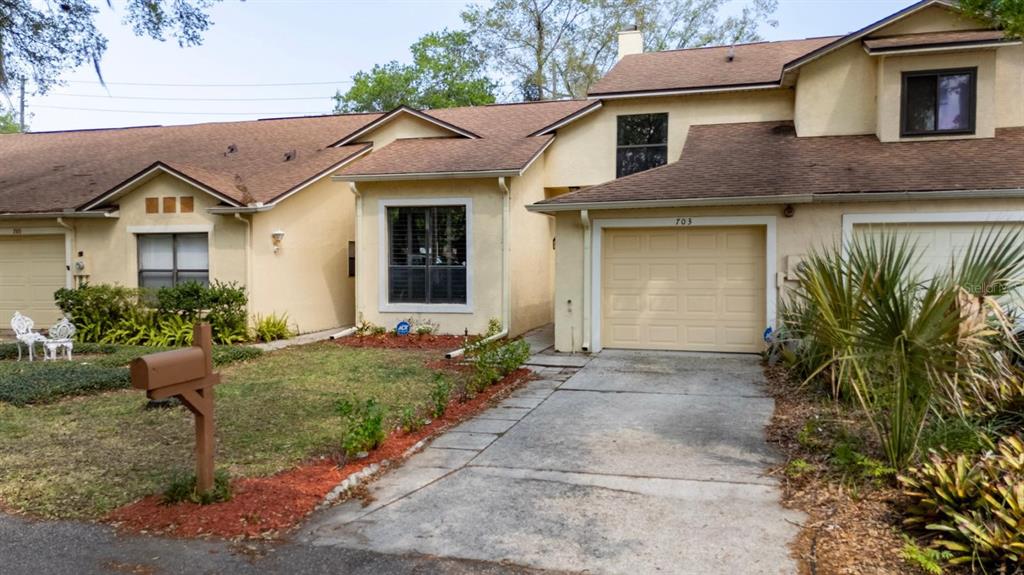 A two-story townhouse with a tan stucco exterior, a single-car garage, and a front yard — 703 SWAN LANE, ALTAMONTE SPRINGS, FL
