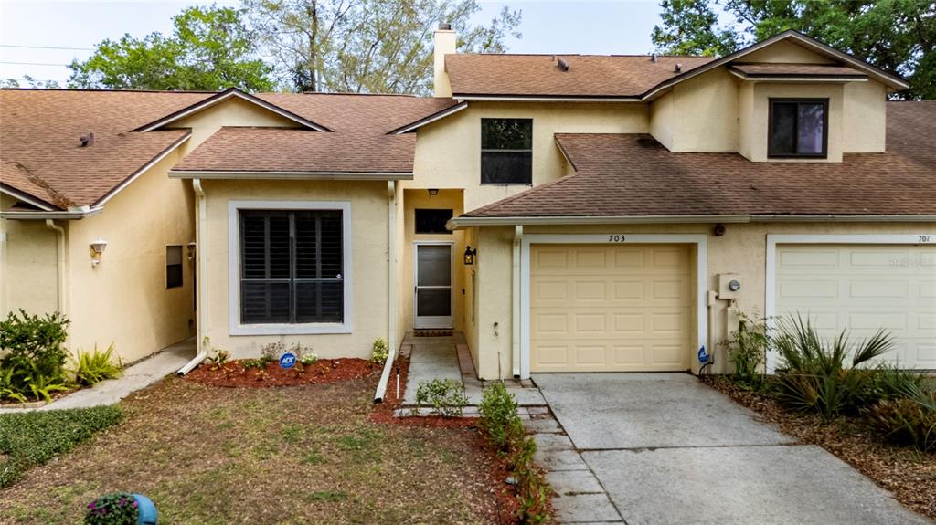 A two-story townhouse with a beige stucco exterior, a single-car garage, and a front walkway — 703 SWAN LANE, ALTAMONTE SPRINGS, FL