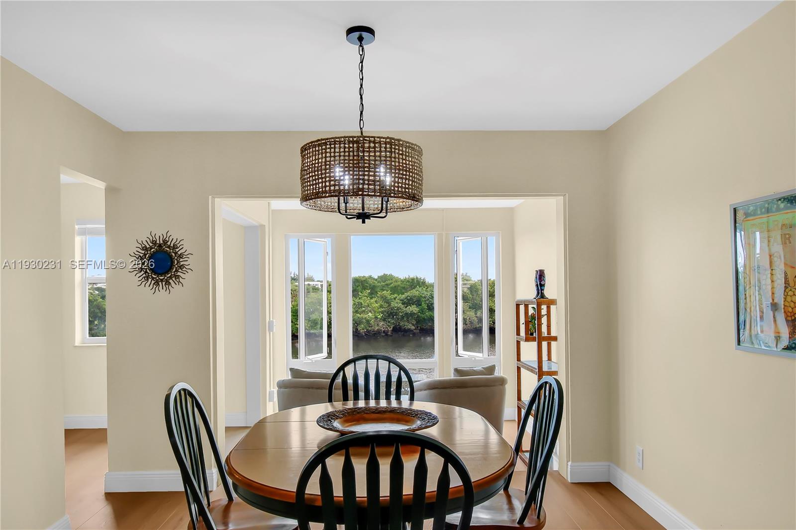 A dining room features a wooden table, black chairs, a woven chandelier, and water views — 7 Colonial Club Drive # 302, Boynton Beach FL 33435, BOYNTON BEACH, FL