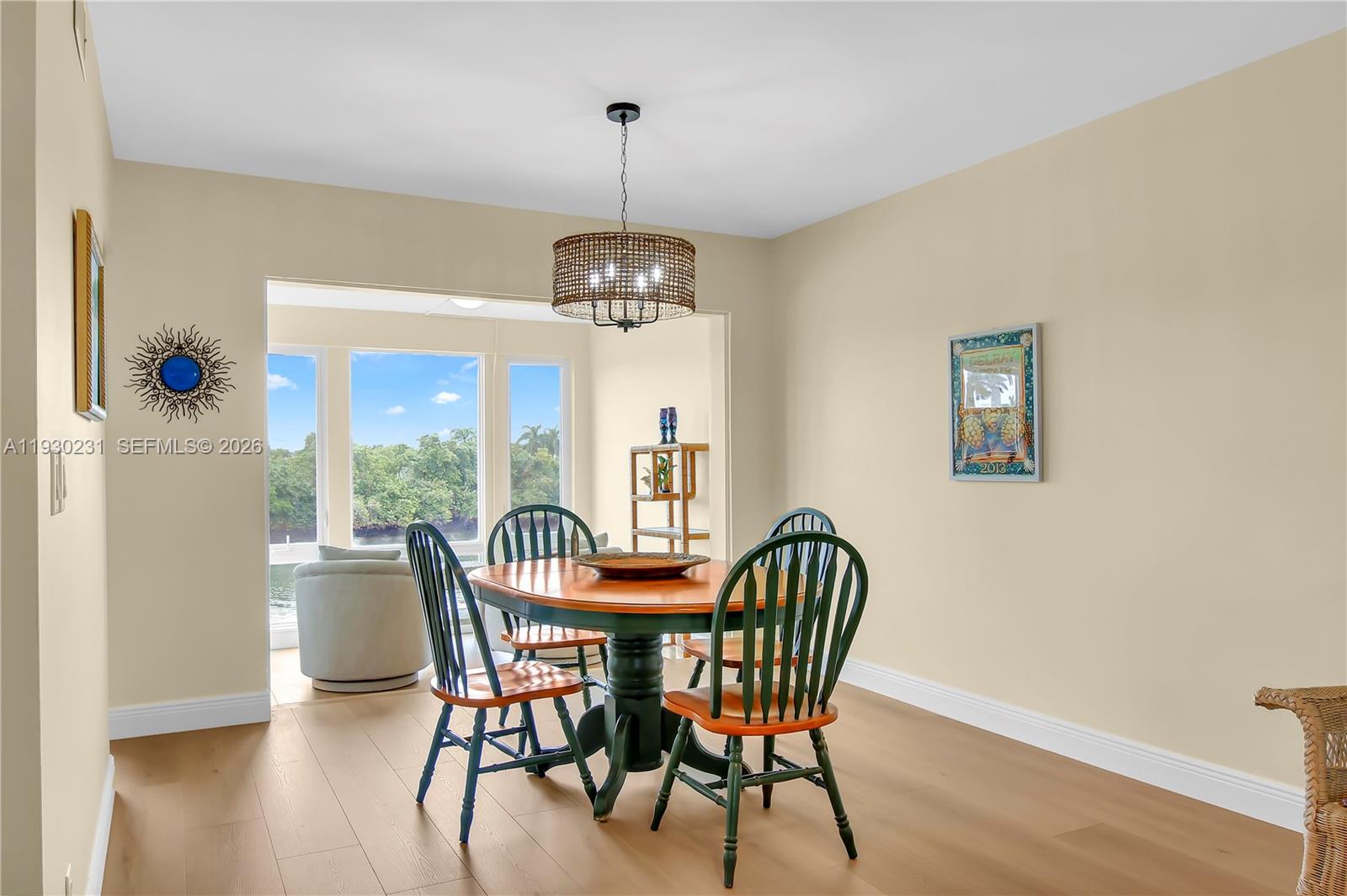 A dining room features a round wooden table, green chairs, and a woven chandelier — 7 Colonial Club Drive # 302, Boynton Beach FL 33435, BOYNTON BEACH, FL