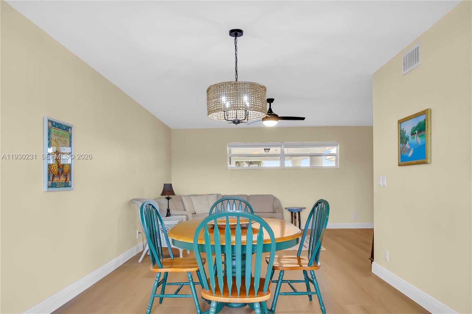 A dining area features a round wooden table with teal chairs under a drum chandelier — 7 Colonial Club Drive # 302, Boynton Beach FL 33435, BOYNTON BEACH, FL