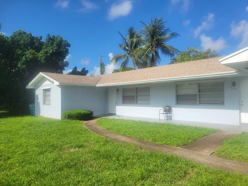 A light blue single-story house features a tan shingled roof and a curved concrete walkway — 242 SE 24th Avenue, Boynton Beach FL 33435, BOYNTON BEACH, FL