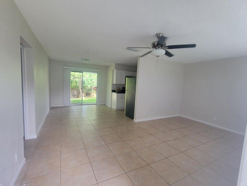 An open-concept living area features light tile flooring, a ceiling fan, and a sliding glass door — 242 SE 24th Avenue, Boynton Beach FL 33435, BOYNTON BEACH, FL