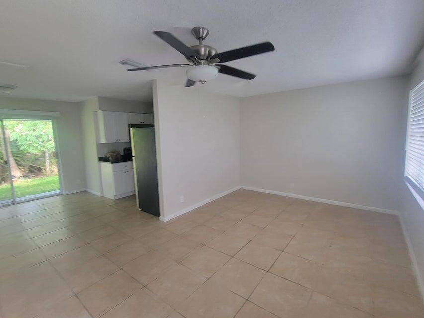 An open-concept living area features light-colored tile flooring, a ceiling fan, and a kitchen corner — 242 SE 24th Avenue, Boynton Beach FL 33435, BOYNTON BEACH, FL