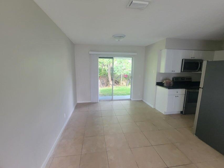 A dining area with tile flooring leads to a sliding glass door opening to a yard — 242 SE 24th Avenue, Boynton Beach FL 33435, BOYNTON BEACH, FL