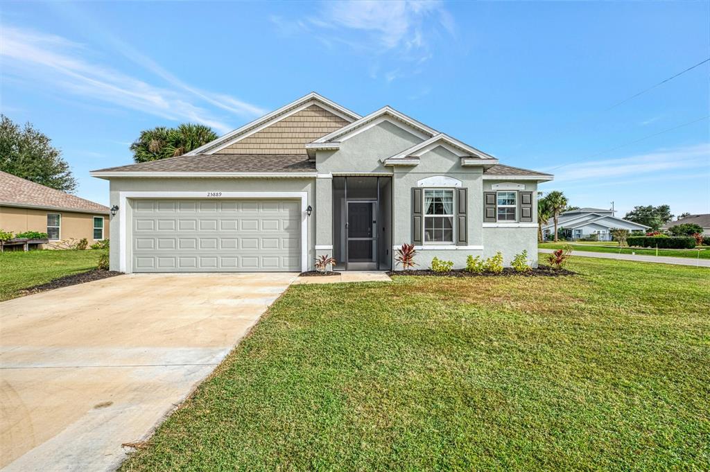 A single-story house with a two-car garage, light-colored stucco exterior, and a front entryway — 25889 AYSEN DRIVE, PUNTA GORDA, FL