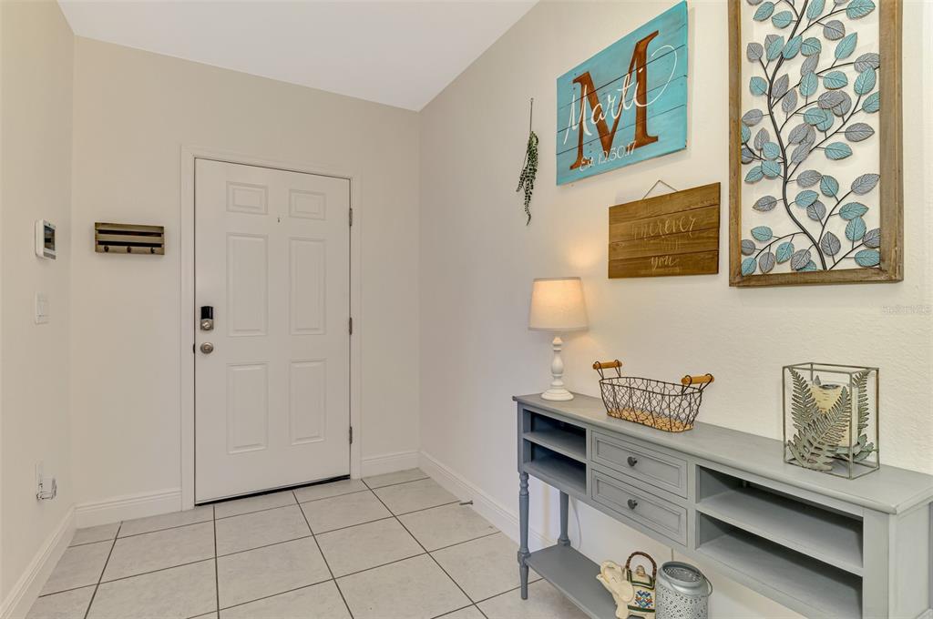An entryway features a white door, tiled floor, and a gray console table with decor — 25889 AYSEN DRIVE, PUNTA GORDA, FL
