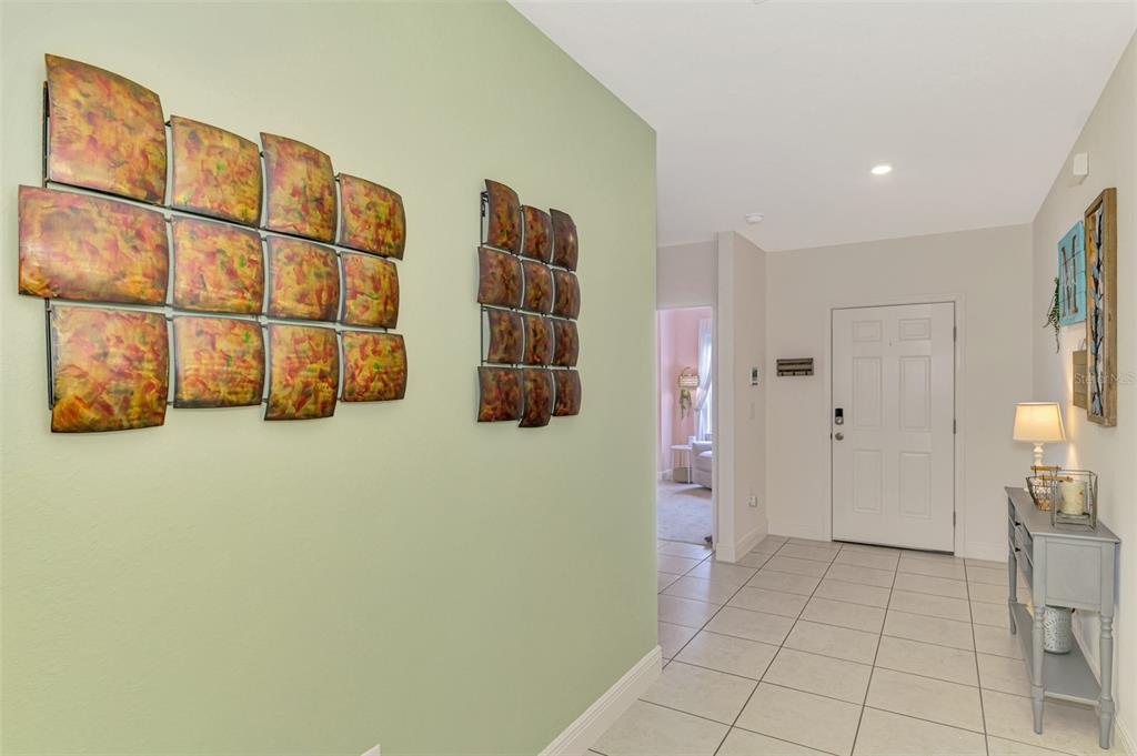 An entryway with tile flooring, a console table, and metal wall art on a green wall — 25889 AYSEN DRIVE, PUNTA GORDA, FL